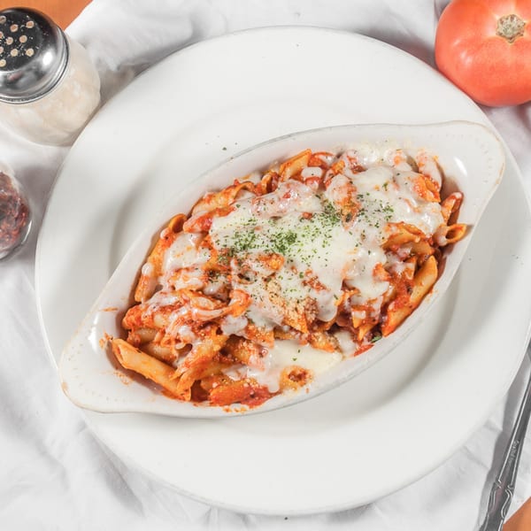 Baked penne pasta with melted mozzarella cheese and red sauce, garnished with parsley.