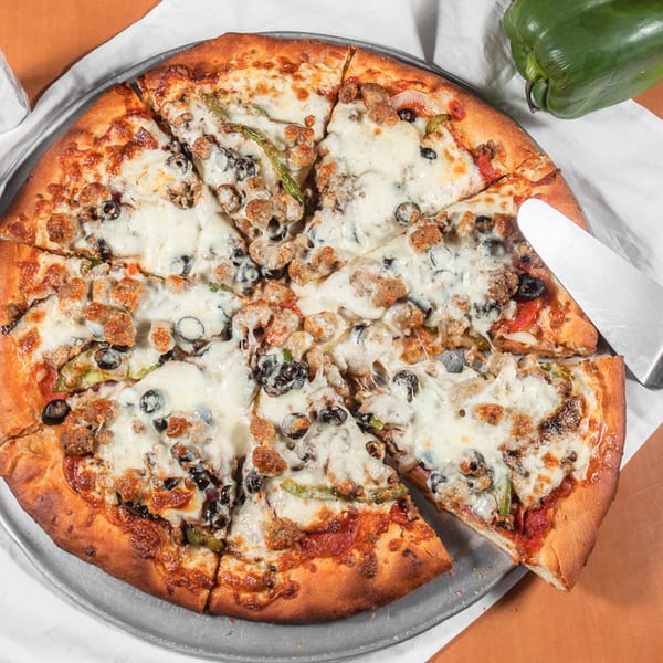 Marri's Pizza Orange's whole pizza with sausage, olives, and green peppers, with one slice being served.