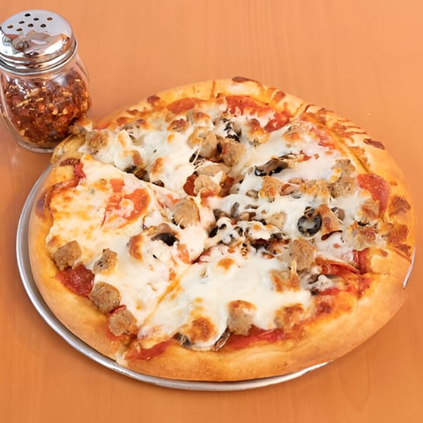 A Marri's Pizza Orange pizza with pepperoni, sausage, mushrooms, and olives, with a shaker of red pepper flakes.